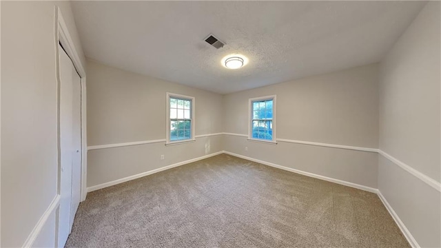 carpeted empty room with a textured ceiling