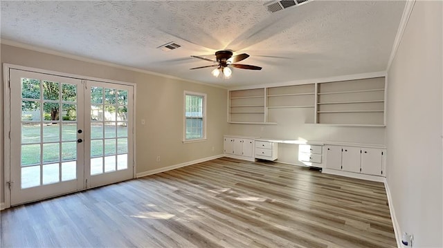 interior space featuring built in desk, crown molding, light hardwood / wood-style flooring, and a textured ceiling