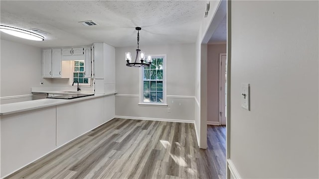 kitchen with white cabinets, a healthy amount of sunlight, light wood-type flooring, and pendant lighting