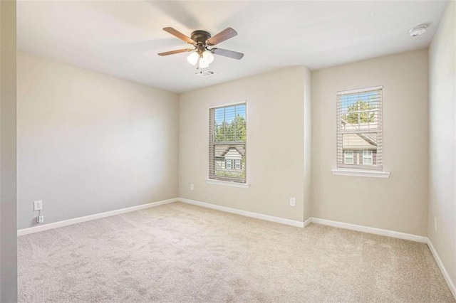 empty room with a healthy amount of sunlight, light colored carpet, and ceiling fan