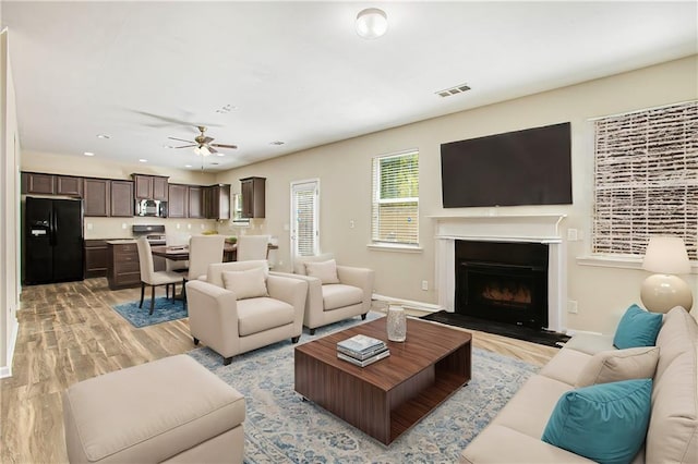 living room with light hardwood / wood-style floors and ceiling fan