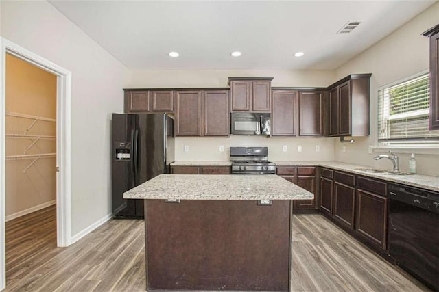 kitchen with black appliances, sink, a center island, dark hardwood / wood-style flooring, and dark brown cabinetry