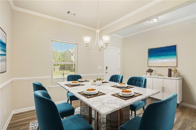 dining room featuring crown molding, hardwood / wood-style flooring, and a chandelier