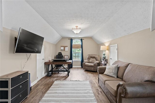 living room with a textured ceiling, vaulted ceiling, and hardwood / wood-style flooring