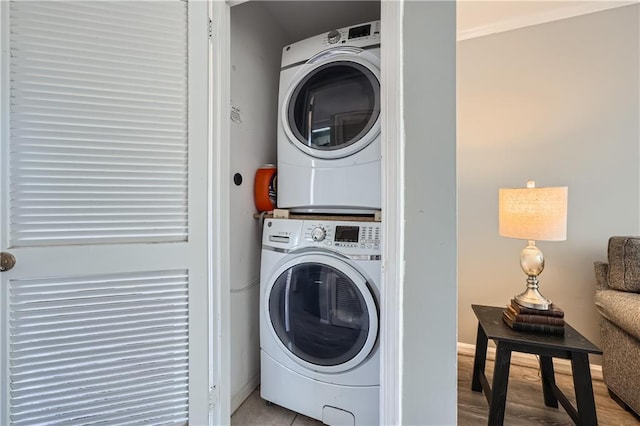 washroom with stacked washer and dryer, laundry area, light wood-style floors, and baseboards