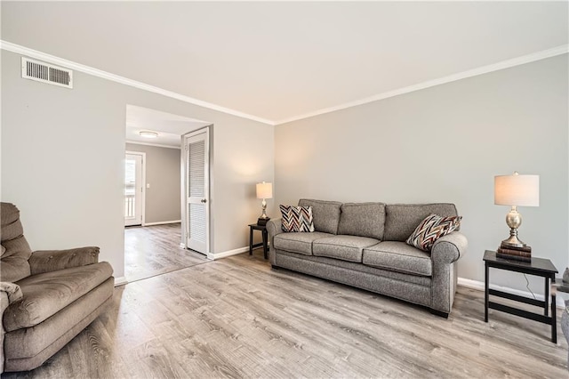 living room with baseboards, ornamental molding, visible vents, and light wood-style floors