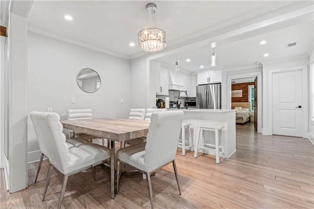 dining room with ornamental molding, a chandelier, and light hardwood / wood-style floors