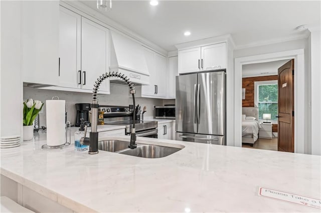 kitchen with white cabinetry, tasteful backsplash, ornamental molding, appliances with stainless steel finishes, and light stone countertops