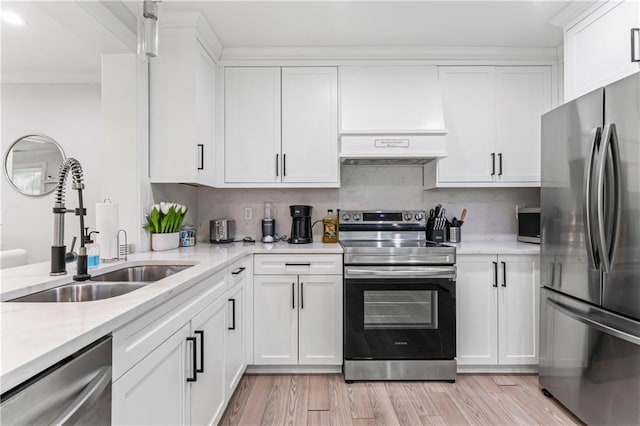 kitchen featuring stainless steel appliances, white cabinetry, sink, and light hardwood / wood-style floors