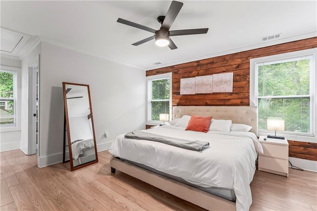 bedroom with ceiling fan, ornamental molding, light hardwood / wood-style flooring, and wood walls