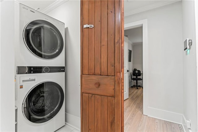 clothes washing area featuring crown molding, stacked washer / drying machine, and light hardwood / wood-style floors