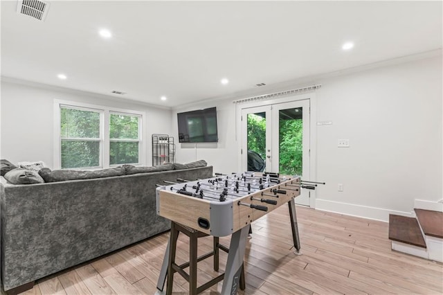 recreation room with crown molding, plenty of natural light, and light wood-type flooring