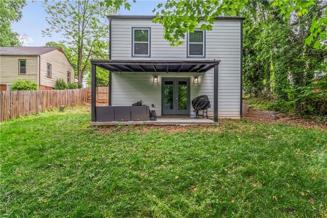 rear view of house with french doors, a patio area, and a lawn