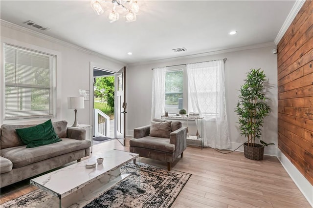 living room with crown molding, a notable chandelier, light hardwood / wood-style flooring, and wood walls