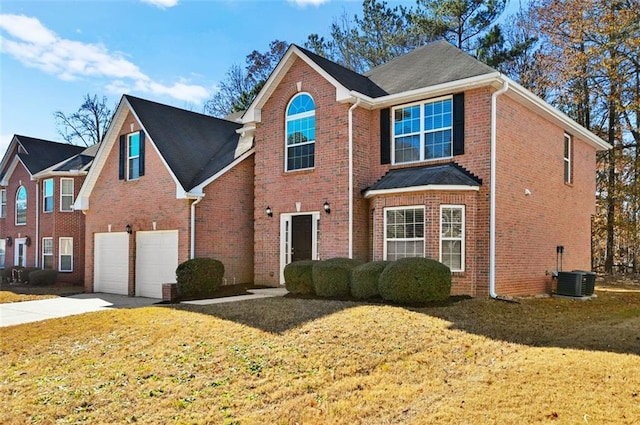 front facade featuring a garage, a front yard, and central air condition unit