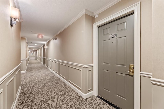 corridor featuring a wainscoted wall, a decorative wall, carpet flooring, and crown molding