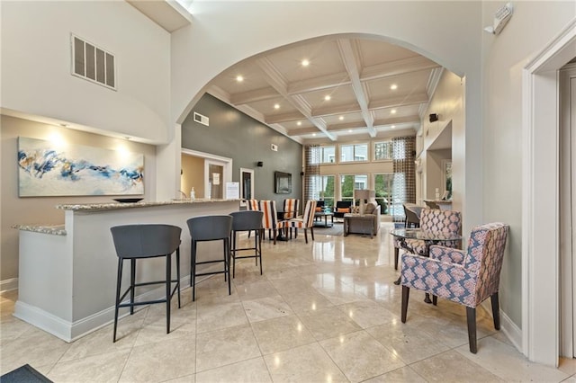 interior space with visible vents, beam ceiling, coffered ceiling, and a towering ceiling