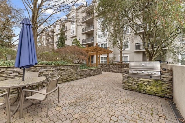 view of property's community featuring exterior kitchen, outdoor dining space, a patio area, and a pergola