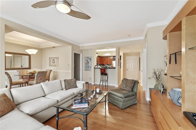 living room with crown molding, a raised ceiling, light wood-style floors, ceiling fan, and baseboards