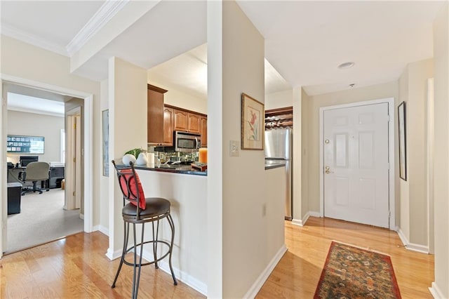 kitchen featuring light wood finished floors, appliances with stainless steel finishes, dark countertops, and brown cabinets