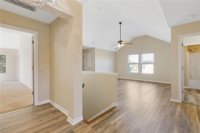 hallway with a wealth of natural light, lofted ceiling, and light hardwood / wood-style flooring