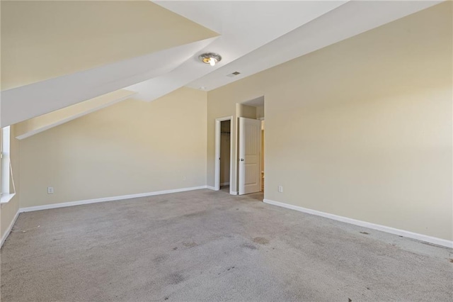 additional living space featuring vaulted ceiling and light colored carpet