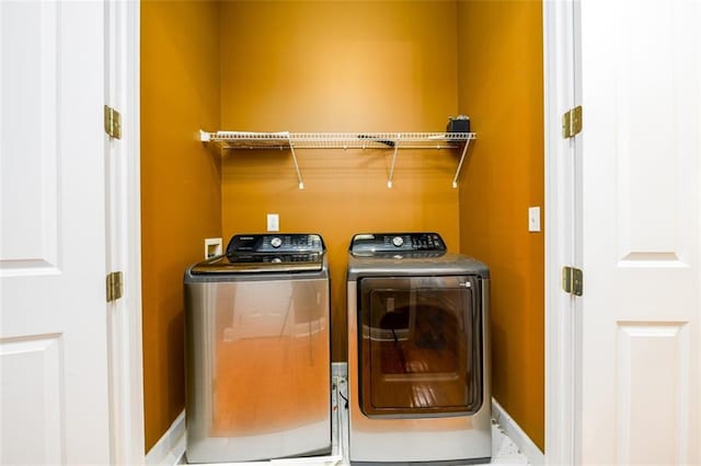 clothes washing area with separate washer and dryer and baseboards