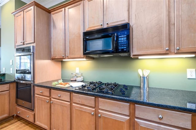 kitchen with black appliances, dark stone countertops, light wood-type flooring, and brown cabinetry