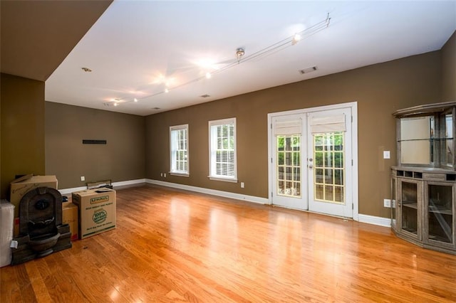 unfurnished living room featuring wood finished floors, plenty of natural light, and baseboards