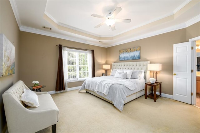bedroom featuring a tray ceiling, ornamental molding, light colored carpet, baseboards, and ceiling fan