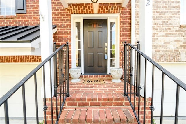 view of exterior entry featuring brick siding and a garage