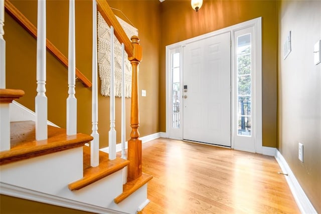entryway with stairway, wood finished floors, and baseboards