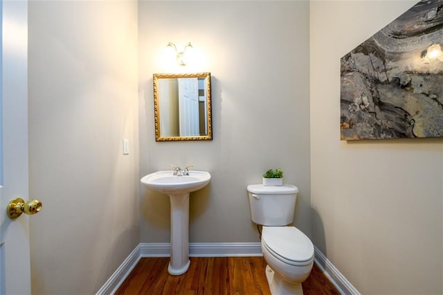bathroom with wood finished floors, baseboards, and toilet