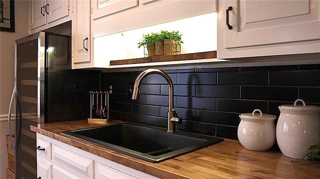 kitchen featuring white cabinetry, wood counters, sink, and decorative backsplash