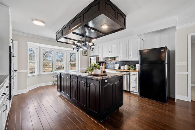 kitchen with tasteful backsplash, a kitchen island, white cabinets, and black fridge