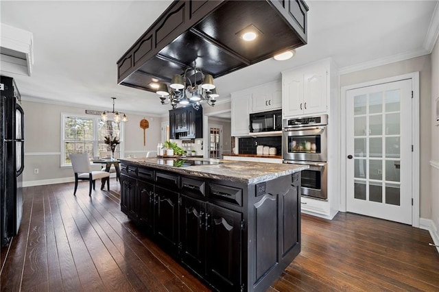 kitchen featuring crown molding, an inviting chandelier, a center island with sink, pendant lighting, and black appliances