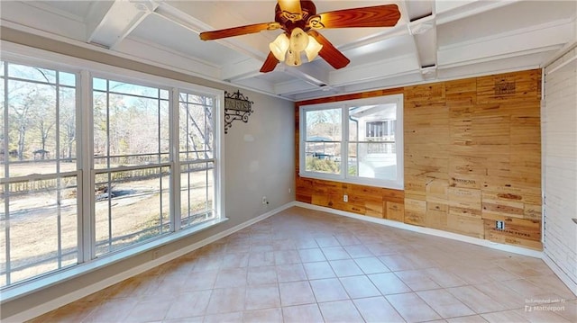 unfurnished room with coffered ceiling, a wealth of natural light, and wood walls