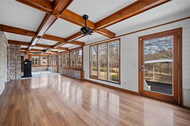 unfurnished living room featuring ceiling fan, coffered ceiling, light hardwood / wood-style floors, beamed ceiling, and wood walls