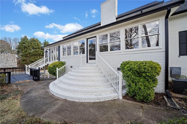 view of exterior entry with a deck and central air condition unit