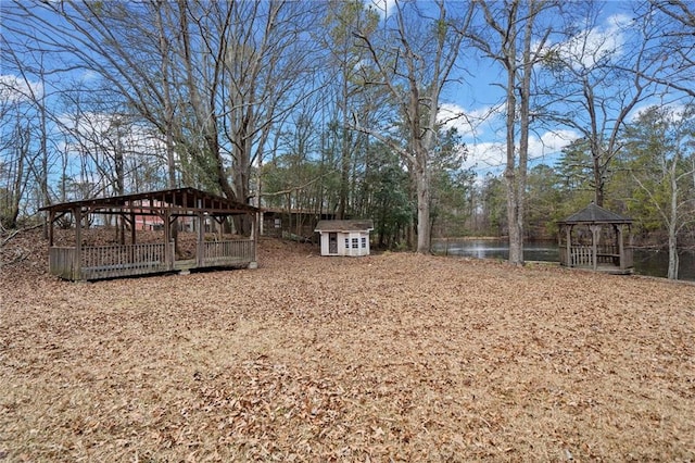 view of yard featuring a gazebo, a water view, and a storage shed