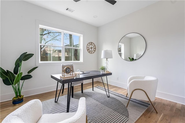 office space with visible vents, baseboards, a ceiling fan, and wood finished floors