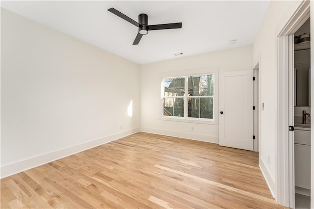 spare room with light wood finished floors, visible vents, a ceiling fan, and baseboards