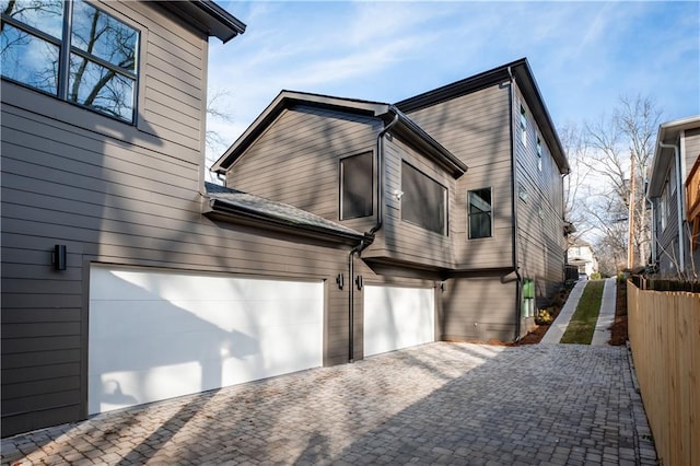 exterior space with decorative driveway, an attached garage, and fence