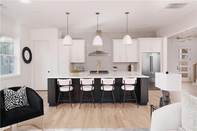 kitchen with white cabinetry, light countertops, an island with sink, and a kitchen bar