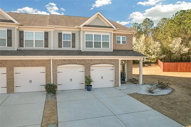 view of front facade featuring brick siding, concrete driveway, an attached garage, and fence