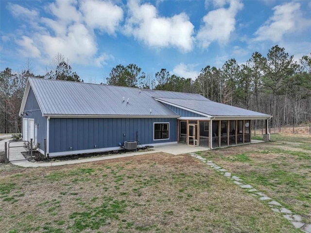 rear view of house featuring a patio, central air condition unit, a sunroom, a lawn, and a garage