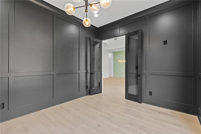 unfurnished room featuring light hardwood / wood-style floors and a notable chandelier