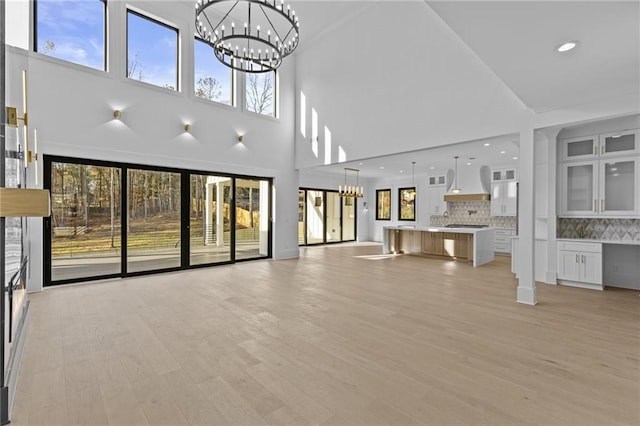 unfurnished living room featuring a wealth of natural light, a towering ceiling, and light hardwood / wood-style floors