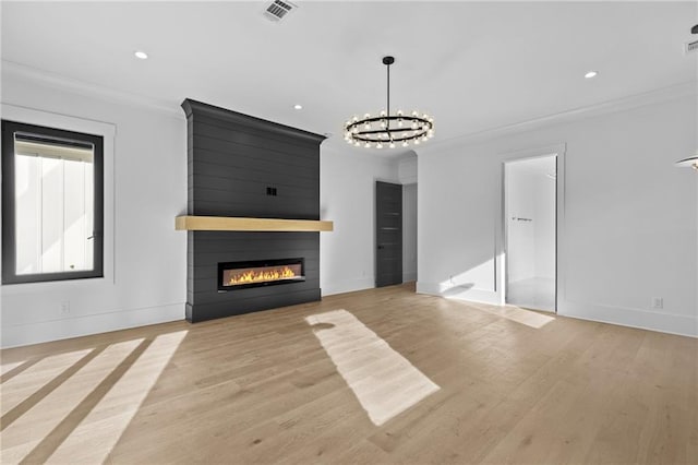 unfurnished living room featuring an inviting chandelier, ornamental molding, a fireplace, and light hardwood / wood-style flooring