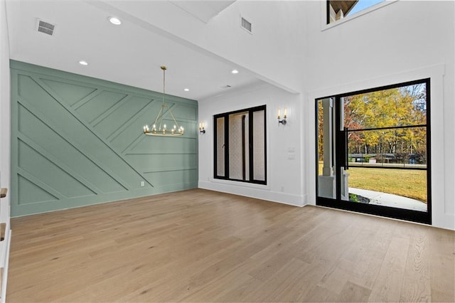 spare room with an inviting chandelier and light hardwood / wood-style flooring